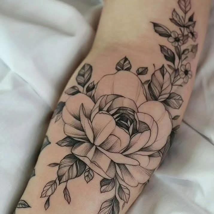 Black and grey fine-line rose and botanical tattoo on an arm