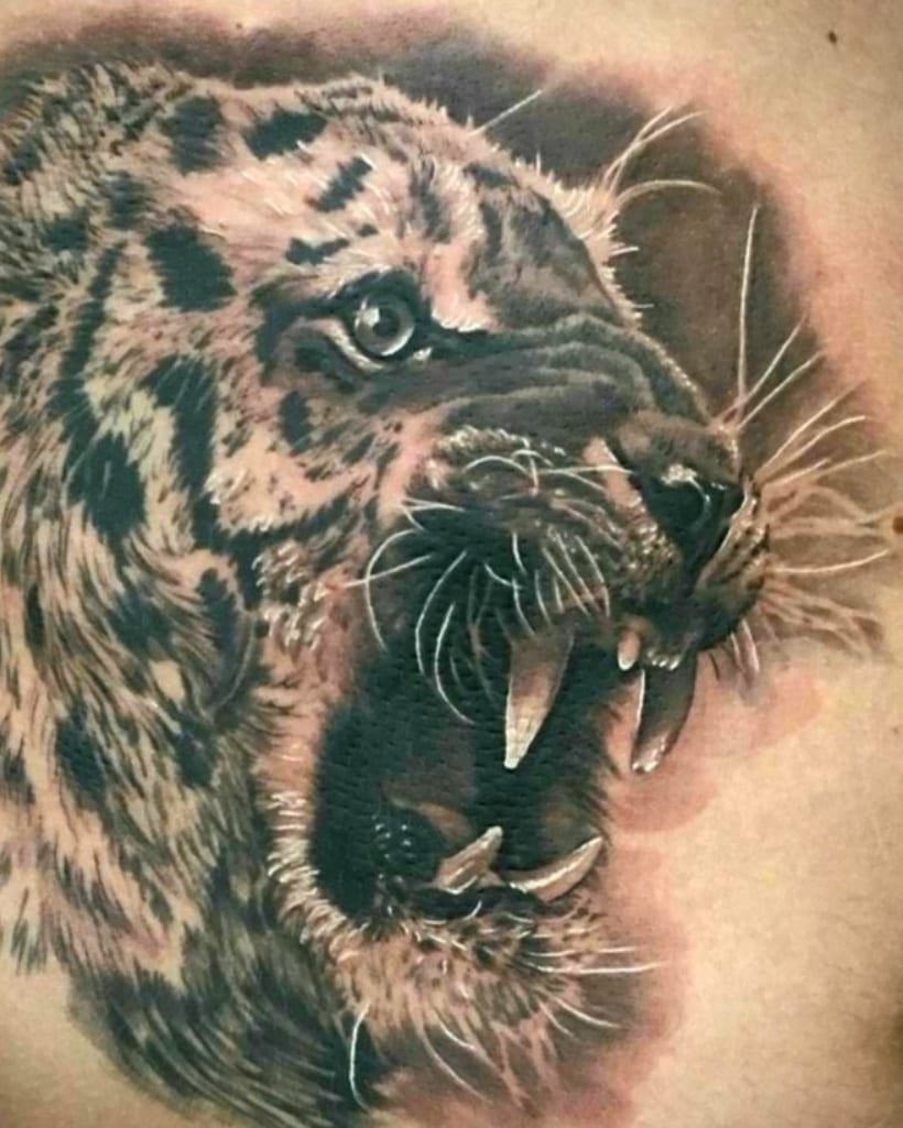 Hyper-realistic roaring leopard or jaguar head tattoo in black and grey